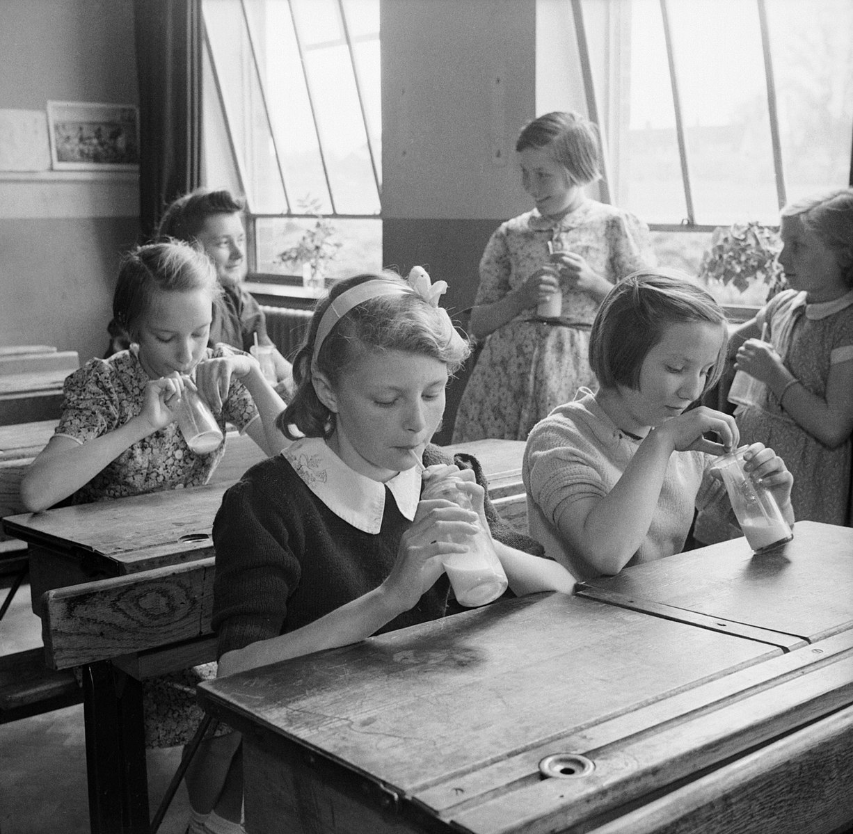 Black and white of girls at Baldock County Council School in Hertfordshire enjoy a drink of milk during a break in the school day in 1944