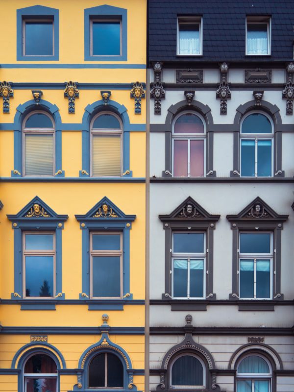 Colour photo of identical town houses painted different colours, yellow and grey