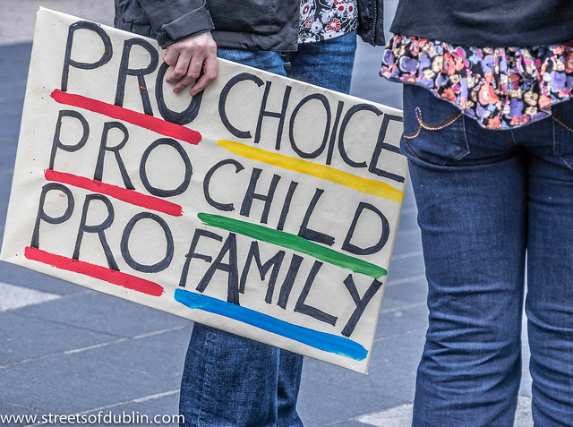 Colour photo of person holding a sign with pro-choice, pro-child, pro-family